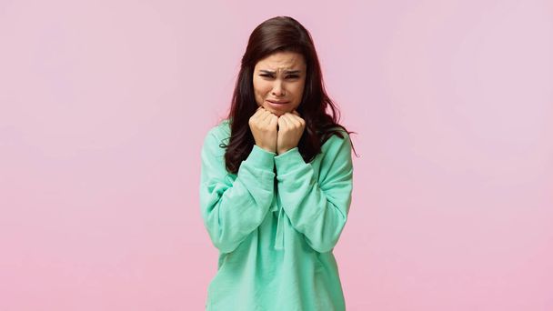 young brunette woman in turquoise hoodie crying isolated on pink  - Photo, Image
