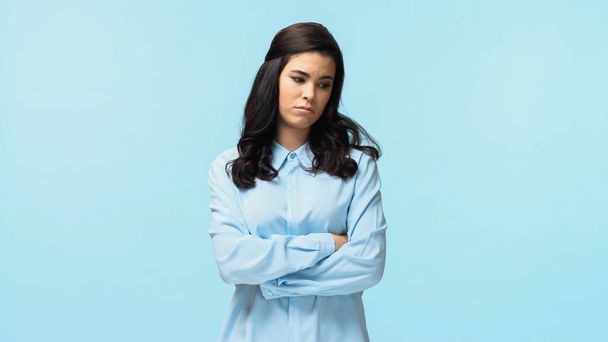 displeased young woman in shirt standing with crossed arms isolated on blue - Foto, Imagem