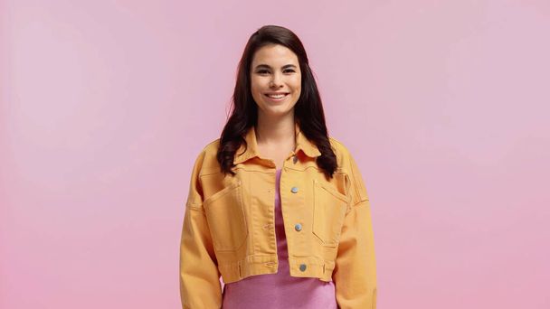 happy young woman in orange denim jacket isolated on pink  - Foto, Imagen
