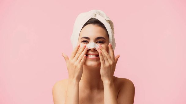 cheerful young woman with towel on head applying patch on nose isolated on pink - Photo, Image