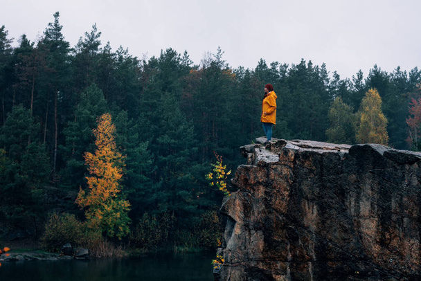 Ragazza con giacca gialla e cappello marrone. Una passeggiata nelle montagne autunnali. Escursioni nelle rocce vicino all'acqua nel Korostyshiv Canyon. - Foto, immagini