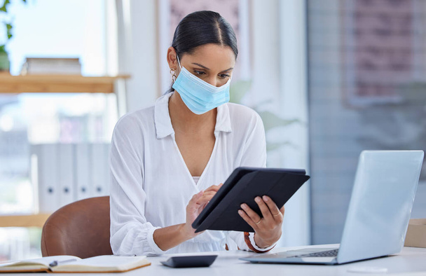 My roles written, I refuse to play in your tragedy. a businesswoman wearing a face mask and using a digital tablet in a modern office - Foto, immagini