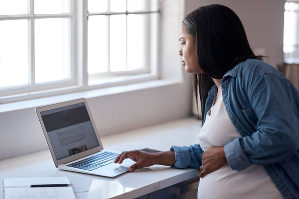 Der Arzt sagte, man solle es ruhig angehen lassen und nicht nichts tun. eine schwangere Frau benutzt ihren Laptop, während sie zu Hause sitzt - Foto, Bild