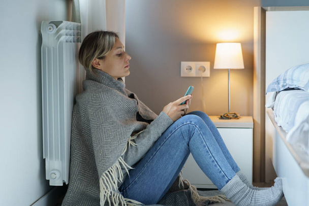 Tired young woman covered with warm blanket searches Internet looking for job to have opportunity to pay bills. Pensive female leaning back on battery wants to prevent bankruptcy trying to find job - Photo, Image