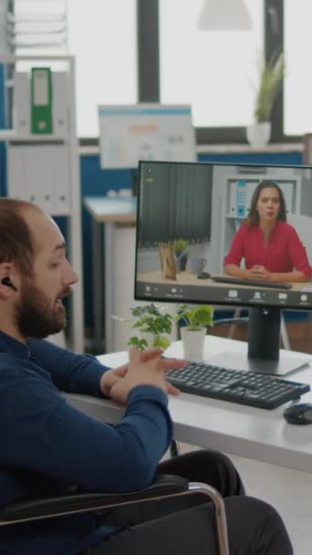 Video vertical: Gerente inválido discapacitado y paralizado hablando con su compañero de trabajo durante la videoconferencia en la reunión en línea de videocall con un socio de negocios sentado en silla de ruedas en la planificación de la oficina de inicio - Metraje, vídeo