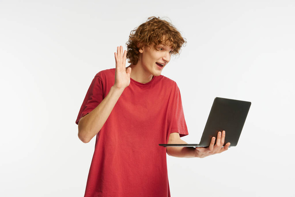 Greetings. Caucasian mans portrait isolated on white background. Emotional boy using laptop for studying. Concept of human emotions, facial expression, sales, online working, fashion. - Fotó, kép