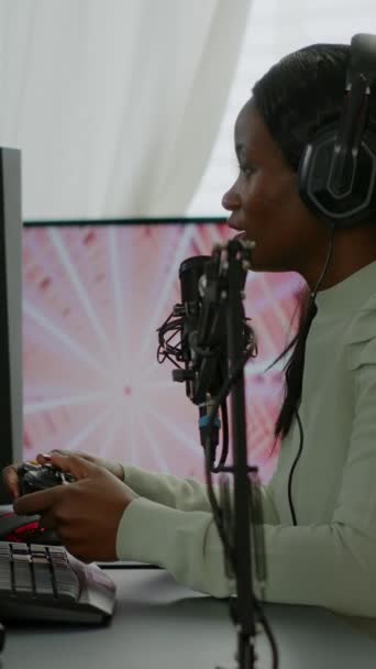 Vertical video: Afro amerikkalainen pelaaja onnellinen voitettuaan virtuaalinen kilpailija käyttäen RGB tehokas tietokone. Online streaming cyber esiintymässä videopelien turnauksen kotona neon valot. - Materiaali, video