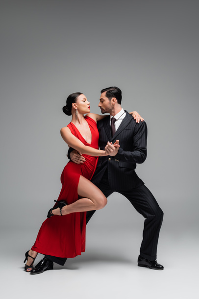 Side view of man dancing tango with elegant partner on grey background - 写真・画像