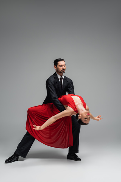 Full length of elegant couple dancing tango on grey background - Foto, immagini