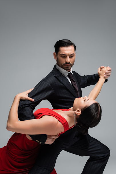 Man in suit dancing tango with brunette partner isolated on grey  - Photo, Image