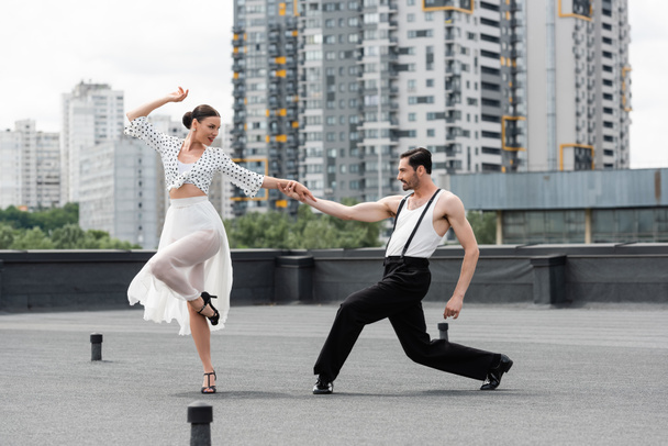 Side view of smiling dancers moving on roof of building outdoors  - Photo, Image