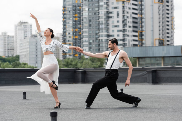 Stilvolle Tänzer bewegen sich tagsüber auf dem Dach des Gebäudes  - Foto, Bild