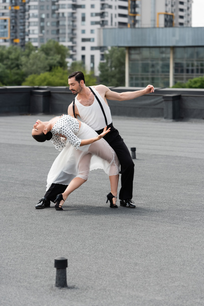 Professional dancer moving with elegant partner on rooftop of building outdoors  - Fotó, kép
