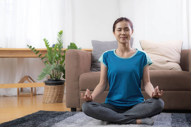 Uśmiechnięta Azjatka ćwicząca jogę w salonie. Samodzielność i trening w domu podczas COVID-19.. - Zdjęcie, obraz