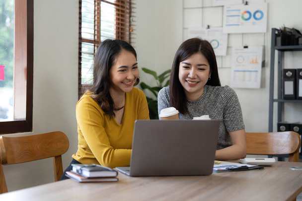 Two young Asian business woman talk, consult, discuss working with new startup project idea presentation analyze plan marketing and investment in the office.. - 写真・画像