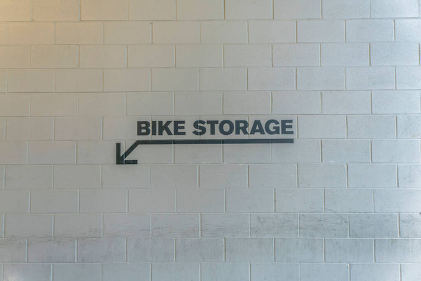 Znak przechowywania rowerów ze strzałką skierowaną w dół na kryty parking. Park dla rowerów znak malowany na białej ścianie budynku do prowadzenia lub informowania rowerzystów w Austin Texas. - Zdjęcie, obraz