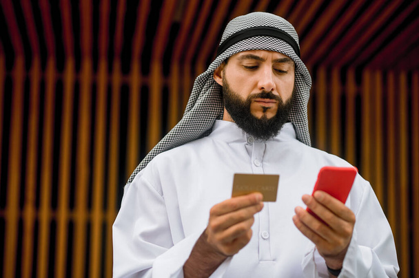 Pago en línea. Un moreno barbudo árabe haciendo pagos en línea - Foto, Imagen