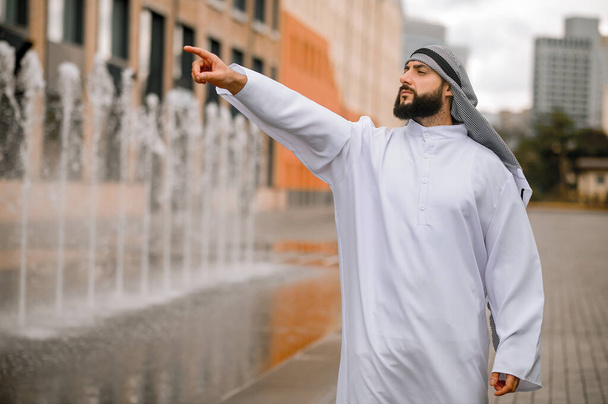 Heiluttaa kättään. Mies perinteisissä arabialaisissa vaatteissa heiluttamassa kättään - Valokuva, kuva