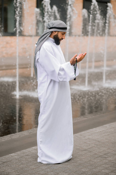 祈りだ。若いですひげを生やしたアラブ人男性で伝統的な服を着て祈る - 写真・画像