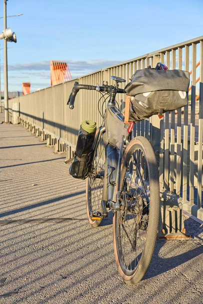 A vertical shot of a bicycle leaning on the sidewalk fence of the Southern Bridge in Riga, Latvia - Foto, Bild