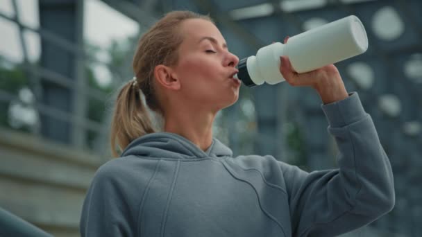 Healthy woman runner tired athlete sportswoman quench thirst after workout sport jogging drink filtered cold water in city park taste protein beverage from bottle body hydration refreshment concept - Footage, Video