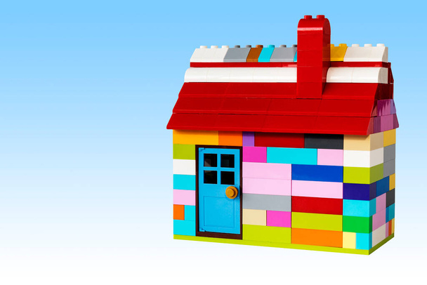 Plastik bloklardan yapılmış renkli bir ev. Baca, çatı ve kapı. Metin için alanı olan mavi gökyüzü arkaplanı - Fotoğraf, Görsel