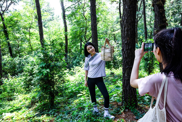 korean young women hiking and plogging_picking up litter, garbage with taking photo - Foto, Imagem