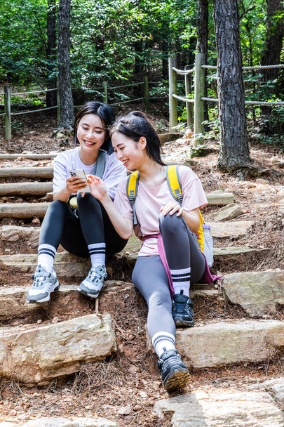 korean young women hiking and plogging_sitting down watching smartphone - Valokuva, kuva