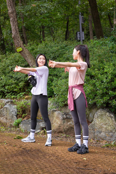 korean young women hiking and plogging_stretch, warm up - Zdjęcie, obraz