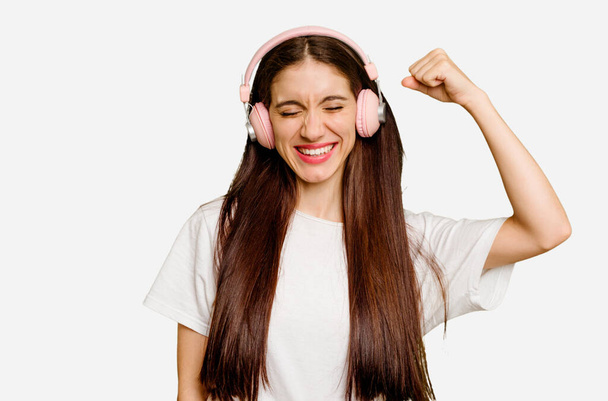 Young caucasian woman wearing headphones isolated raising fist after a victory, winner concept. - Photo, Image