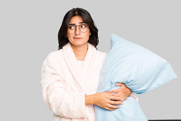 Jeune femme indienne portant un pyjama isolé confus, se sent douteux et incertain. - Photo, image