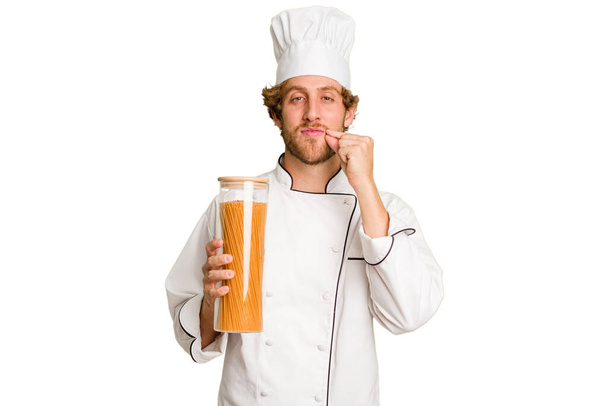 Mladý kuchař muž izolovaný na bílém pozadí s prsty na rtech drží tajemství. - Fotografie, Obrázek