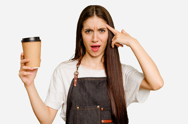 Young barista woman holding a takeaway coffee isolated showing a disappointment gesture with forefinger. - Photo, Image