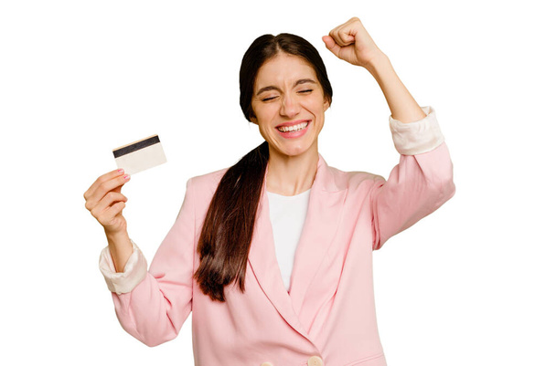 Ділова біла жінка, що тримає кредитну картку, ізольовано піднімає кулак після перемоги, концепція переможця
. - Фото, зображення