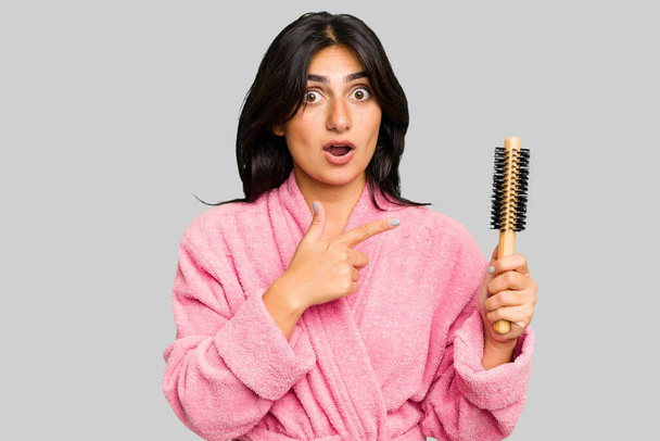 Yanında saç fırçası tutan bornozlu genç Hintli kadın. - Fotoğraf, Görsel