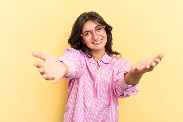 fiatal indiai nő elszigetelt sárga háttér mutató üdvözlő kifejezés. - Fotó, kép