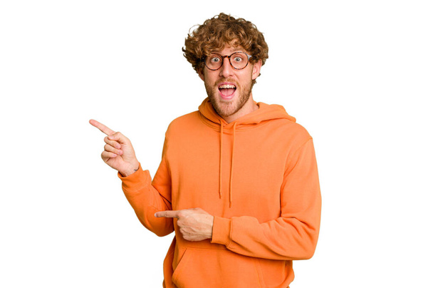 Νεαρός καυκάσιος άνδρας απομονωμένος σε πράσινο χρώμιο φόντο ενθουσιασμένος δείχνοντας με τα μπροστινά δάχτυλα μακριά. - Φωτογραφία, εικόνα