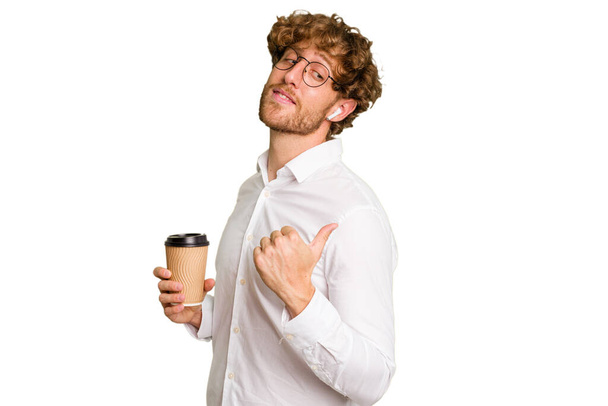 Business caucasian man holding a coffee to take away isolated on white background points with thumb finger away, laughing and carefree. - Foto, imagen