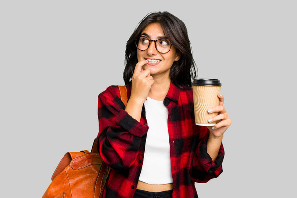 Mladá studentka indická žena drží odnést kávu izolované uvolněné myšlení o něco při pohledu na kopírovací prostor. - Fotografie, Obrázek