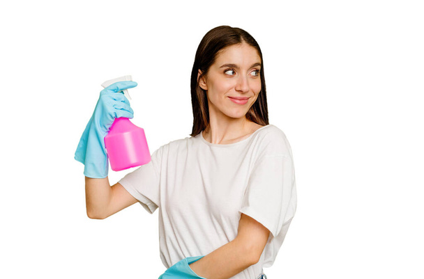 Young cleaner woman isolated looks aside smiling, cheerful and pleasant. - 写真・画像