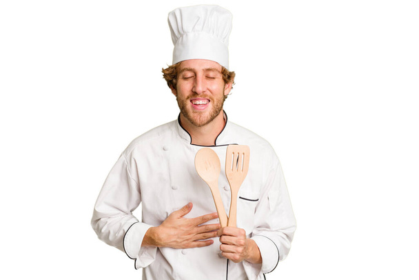 Young cook man isolated on white background laughing and having fun. - Photo, Image