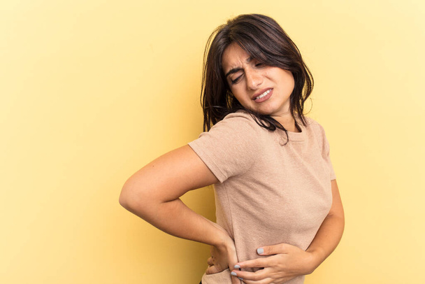 Young Indian woman isolated on yellow background suffering a back pain. - Photo, Image