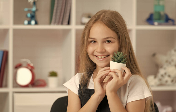 glad child hold potted plant in school classroom. - Photo, Image