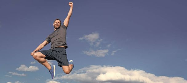 Muž běží a skáče, prapor s kopírovacím prostorem. svalnatý muž skákání ve sportovním oblečení venku na obloze pozadí, úspěch - Fotografie, Obrázek
