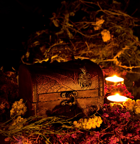 Pecho mágico sobre hierbas secas a la luz de las velas
 - Foto, imagen