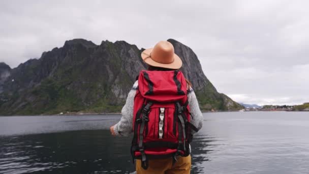 Gelukkige vrouw toerist op de Lofoten eilanden in Noorwegen, bergen en zee achtergrond. - Video