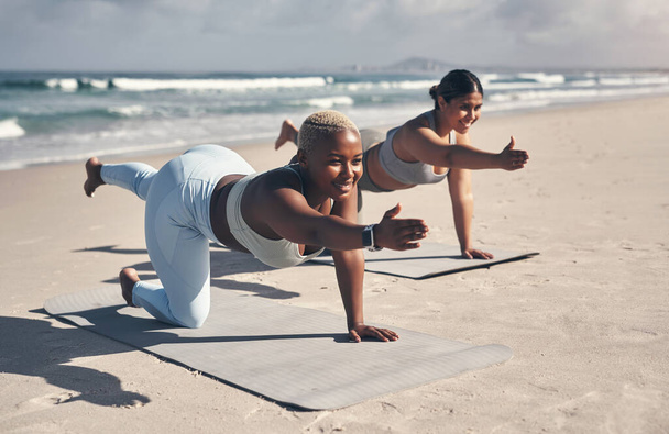 Ihre Muskeln bekommen ein Training, während Ihr Gehirn eine Pause bekommt. zwei junge Frauen praktizieren Yoga am Strand - Foto, Bild