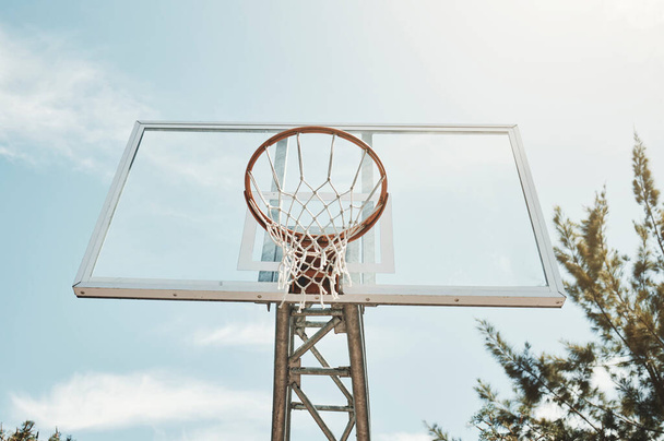 Basketball, sports and fitness with a hoop on a court for a game, match or competitive event outdoor from below. Exercise, training and net with sport equipment outside on a clear blue sky summer day. - Photo, image
