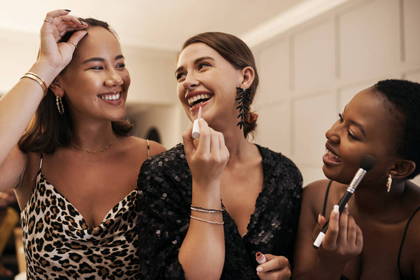 Touching up on that class. a diverse group of friends standing together and doing their makeup during a New Years dinner party - Photo, Image