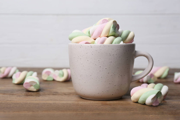 Ceramic cup with colorful marshmallows on wooden table - Foto, Imagem